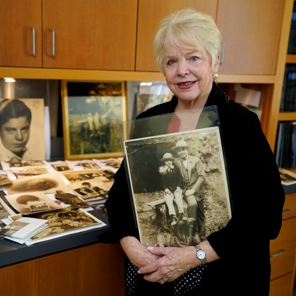 FILE - Diane Capone holds a copy of a photograph of her father, Albert "Sonny" Capone as a young boy and her grandfather Al Capone on display at Witherell's Auction House in Sacramento, Calif., Wednesday, Aug. 25, 2021. (AP Photo/Rich Pedroncelli, File)