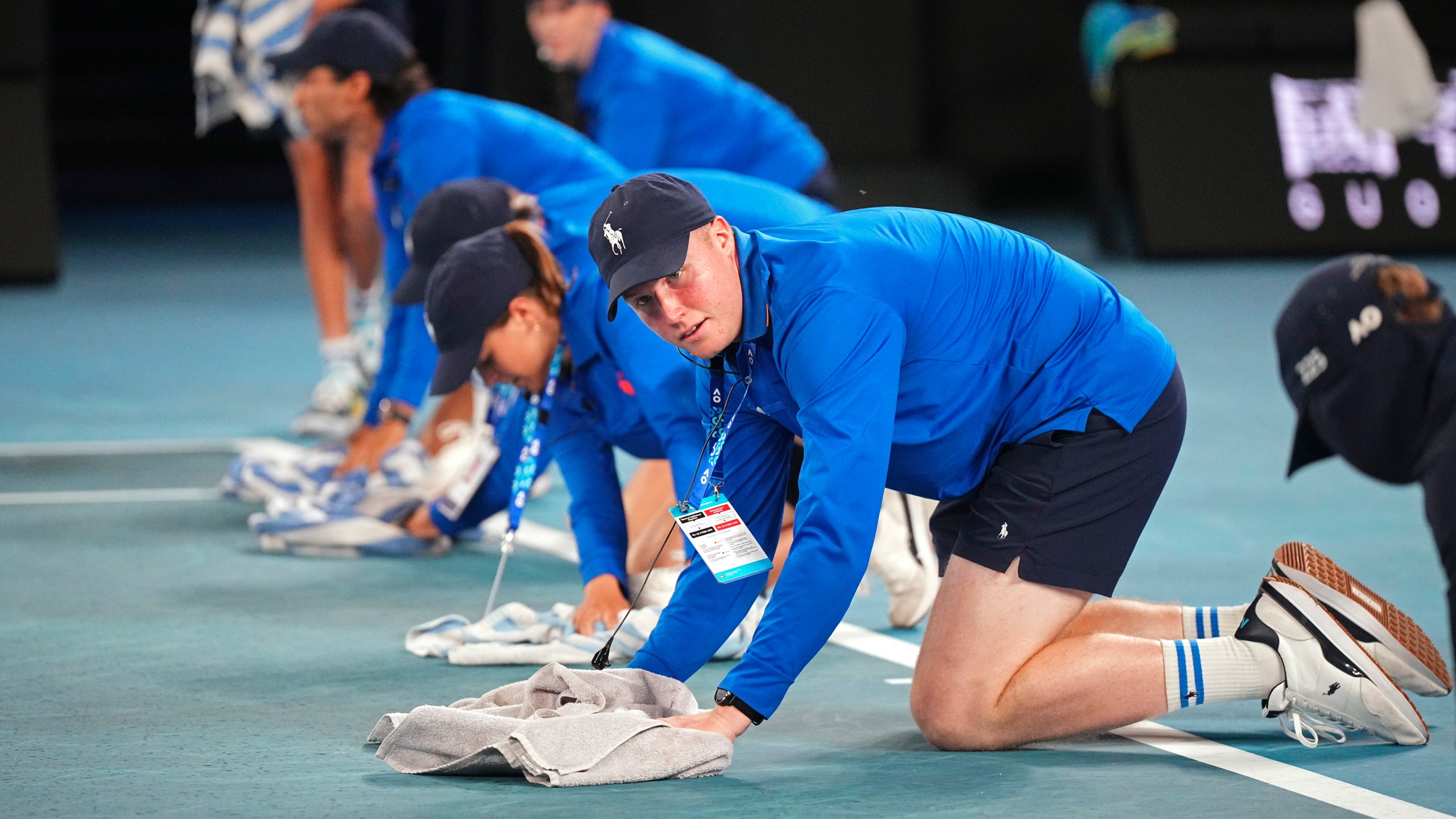 Staff dry the court as rain delays play during the second round match on Rod Laver Arena between Novak Djokovic of Serbia and Jaime Faria of Portugal at the Australian Open tennis championship in Melbourne, Australia, Wednesday, Jan. 15, 2025. (AP Photo/Vincent Thian)