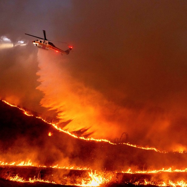 FILE - Water is dropped by helicopter on the Kenneth Fire in the West Hills section of Los Angeles, Jan. 9, 2025. (AP Photo/Ethan Swope, File)