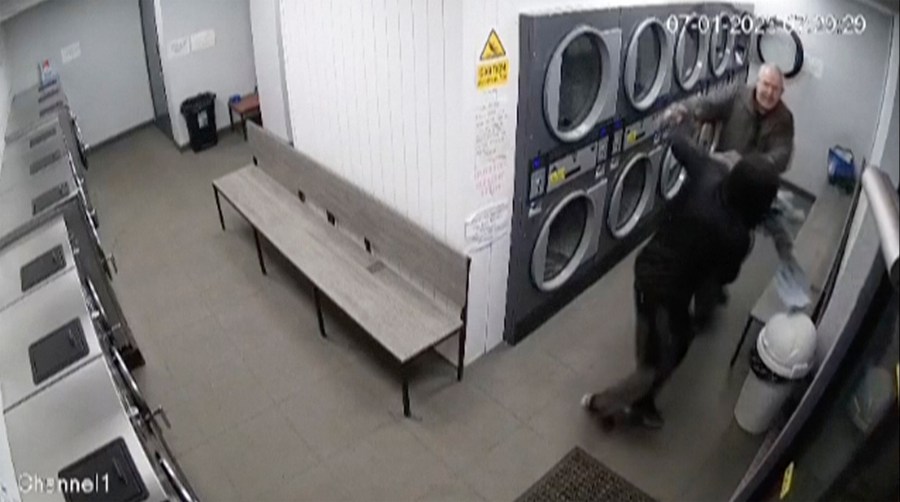 In this grab taken from CCTV from a Launderette in Maltby, a man fights off a mugger with a pair of trousers, in Maltby, England. (CCTV from a Launderette in Maltby via AP)