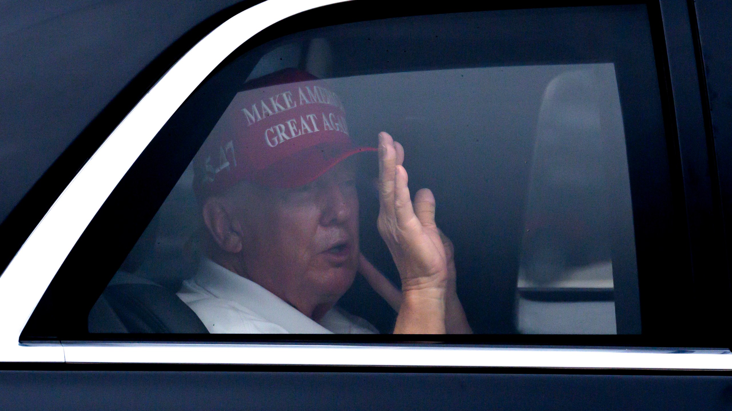 President Donald Trump waves from his vehicle as he arrives at the Trump International Golf Club, Monday, Feb. 17, 2025, in West Palm Beach, Fla. (AP Photo/Ben Curtis)