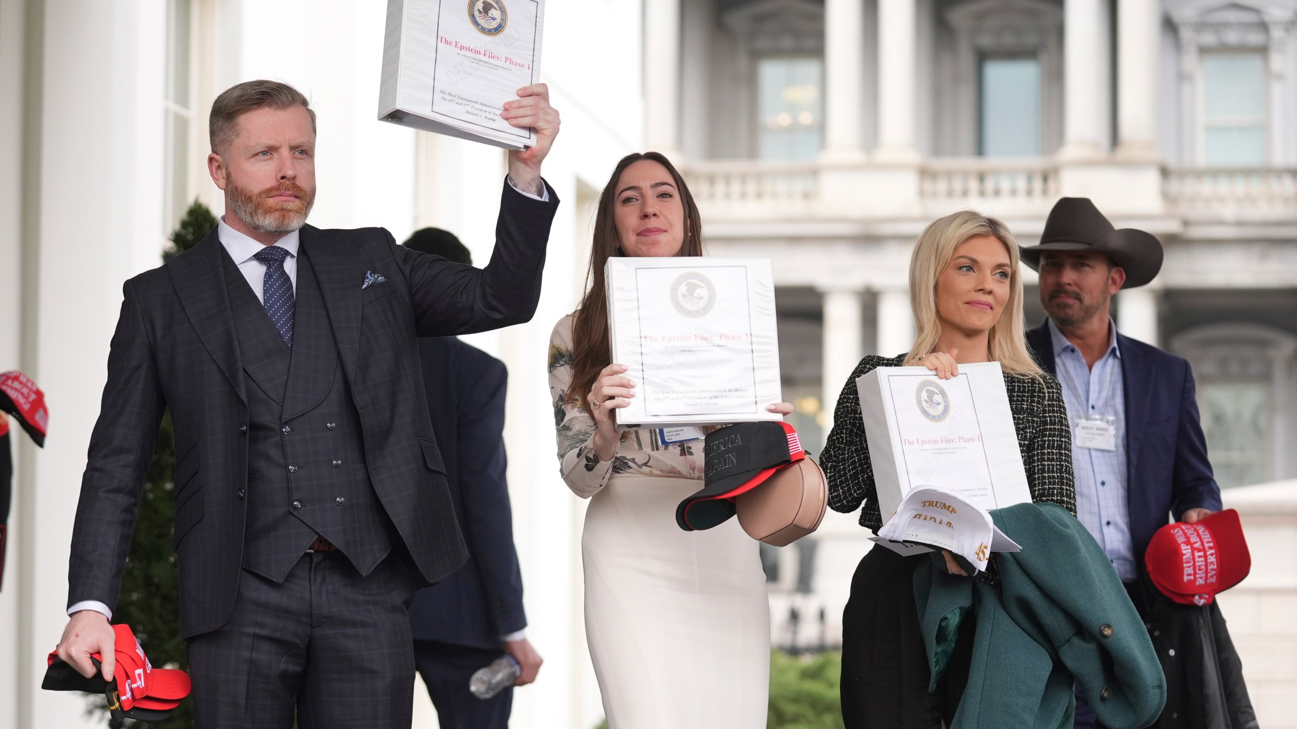 Conservative political commentator Rogan O'Handley, also known as DC Draino, from left, social media content creator Chaya Raichik and conservative political commentator Liz Wheeler hold up binders with a cover titled "The Epstein Files: Phase 1," with Jack Posobiec at the White House, Thursday, Feb. 27, 2025, in Washington. (AP Photo/Evan Vucci)